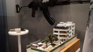 A model of the house where a precision counterterrorism operation killed al-Qaida’s leader Ayman al-Zawahri is displayed below a rifle used by Michael Spann, the first American killed in Afghanistan, in the refurbished museum at the Central Intelligence Agency headquarters building in Langley, Va., on Saturday, Sept. 24, 2022. (AP Photo/Kevin Wolf)