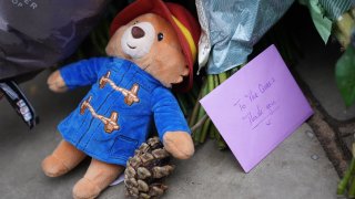 A Paddington bear soft toy and a card lay outside Buckingham Palace