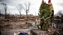 Edward "Roaddawg" Manley, a volunteer and honorary firefighter with the Point Breeze Volunteer Fire Department, places a star on top of a Christmas tree Dec. 25, 2012, in the Breezy Point neighborhood of New York City. Residents are still struggling to recover from a massive fire that destroyed over 100 homes during Superstorm Sandy.