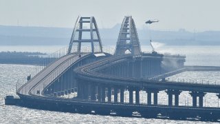 A helicopter drops water to stop fire on Crimean Bridge