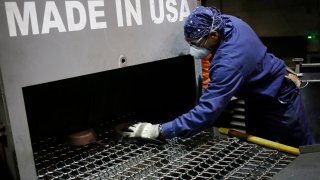 An assembly line worker loads cast iron cookware into machinery at the Lodge Manufacturing factory in South Pittsburg, Tennessee.