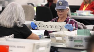 Election workers open mail in ballots at the Maricopa County Tabulation and Election Center in Phoenix on Nov. 11, 2022.