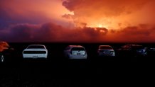 Car are parked near an ancient lava field as a lava flow colors the sky above Mauna Loa, Monday, Nov. 28, 2022, near Hilo, Hawaii. Mauna Loa, the world's largest active volcano erupted Monday for the first time in 38 years. (AP Photo/Marco Garcia)