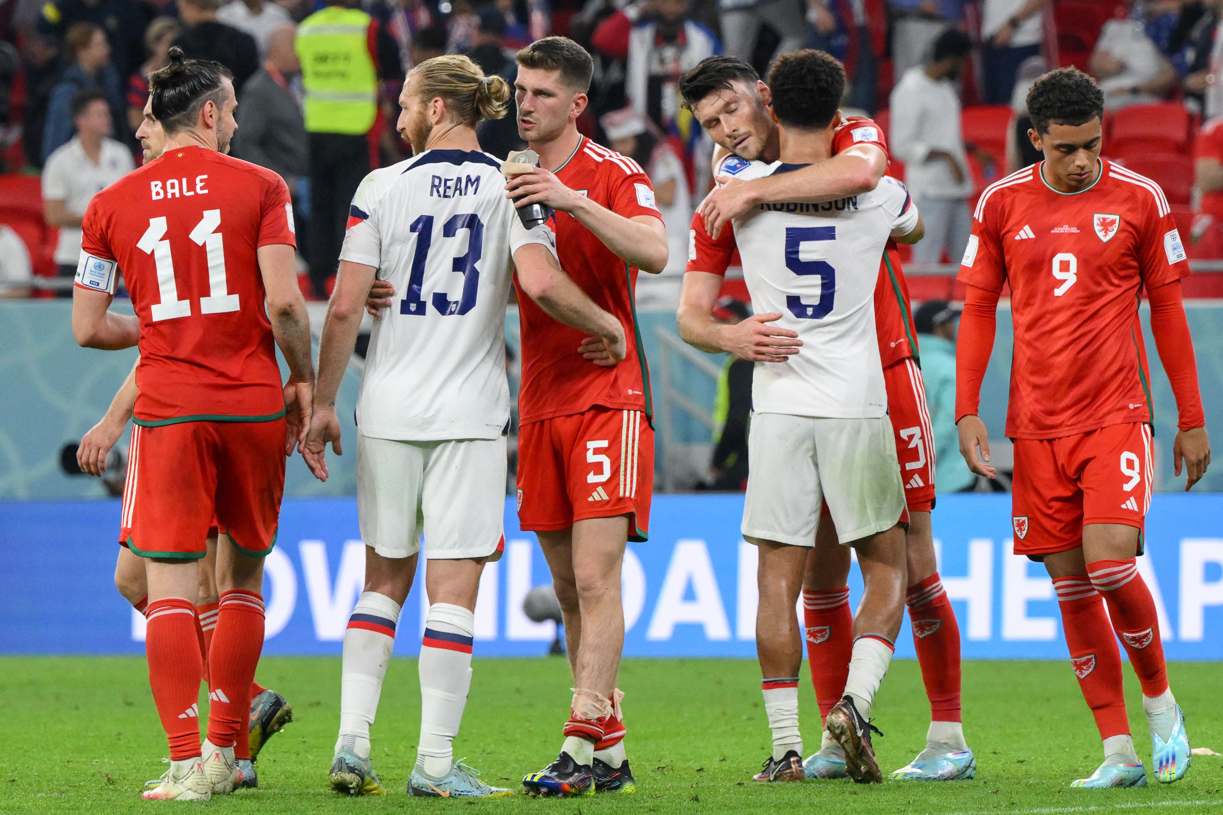 Players greet one another at the end of the Qatar 2022 World Cup Group B football match between USA and Wales at the Ahmad Bin Ali Stadium in Al-Rayyan, west of Doha on Nov. 21, 2022.