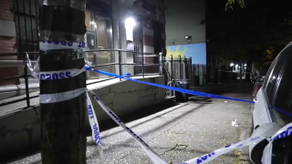 Police tape criss crosses the sidewalk outside a Harlem building.
