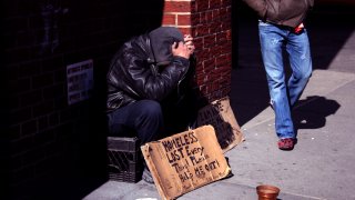 A man walks past a homeless man on a New York City street.