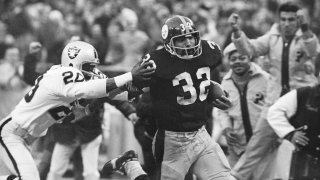 Pittsburgh Steelers’ Franco Harris (32) eludes a tackle by Oakland Raiders’ Jimmy Warren as he runs 42-yards for a touchdown after catching a deflected pass during an AFC Divisional NFL football playoff game in Pittsburgh, Dec. 23, 1972.