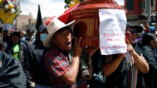 Residents carry a coffin with the name of the deceased