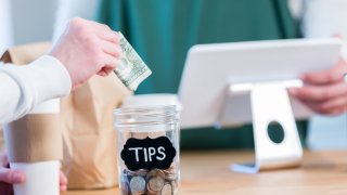 Unrecognizable coffee shop customer using tip jar