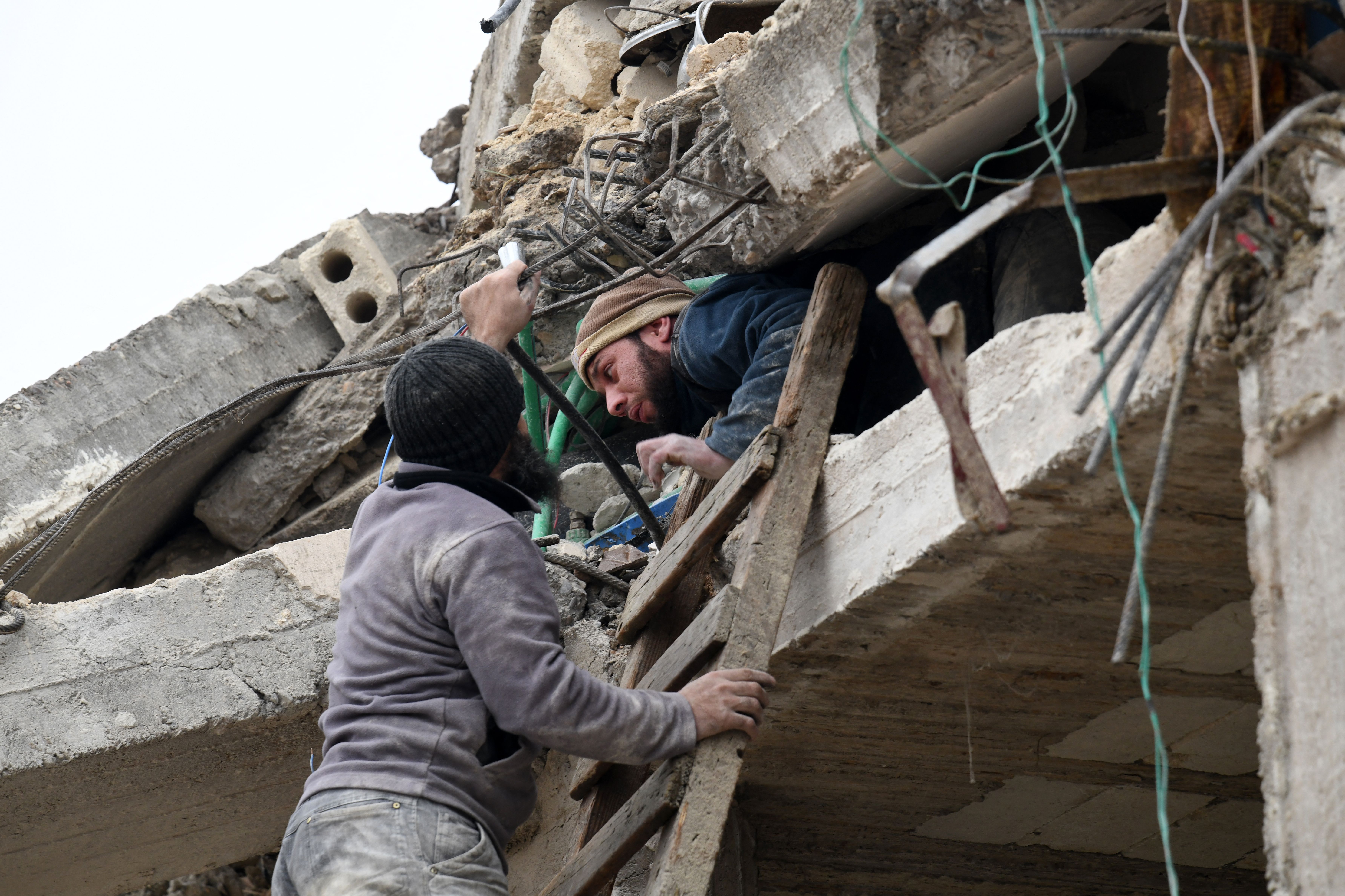 A man helps an injured resident slide out of the rubble of a collapsed building in Jindires, Syria,  Feb. 6, 2023, after a 7.8 magnitude earthquake struck the region.