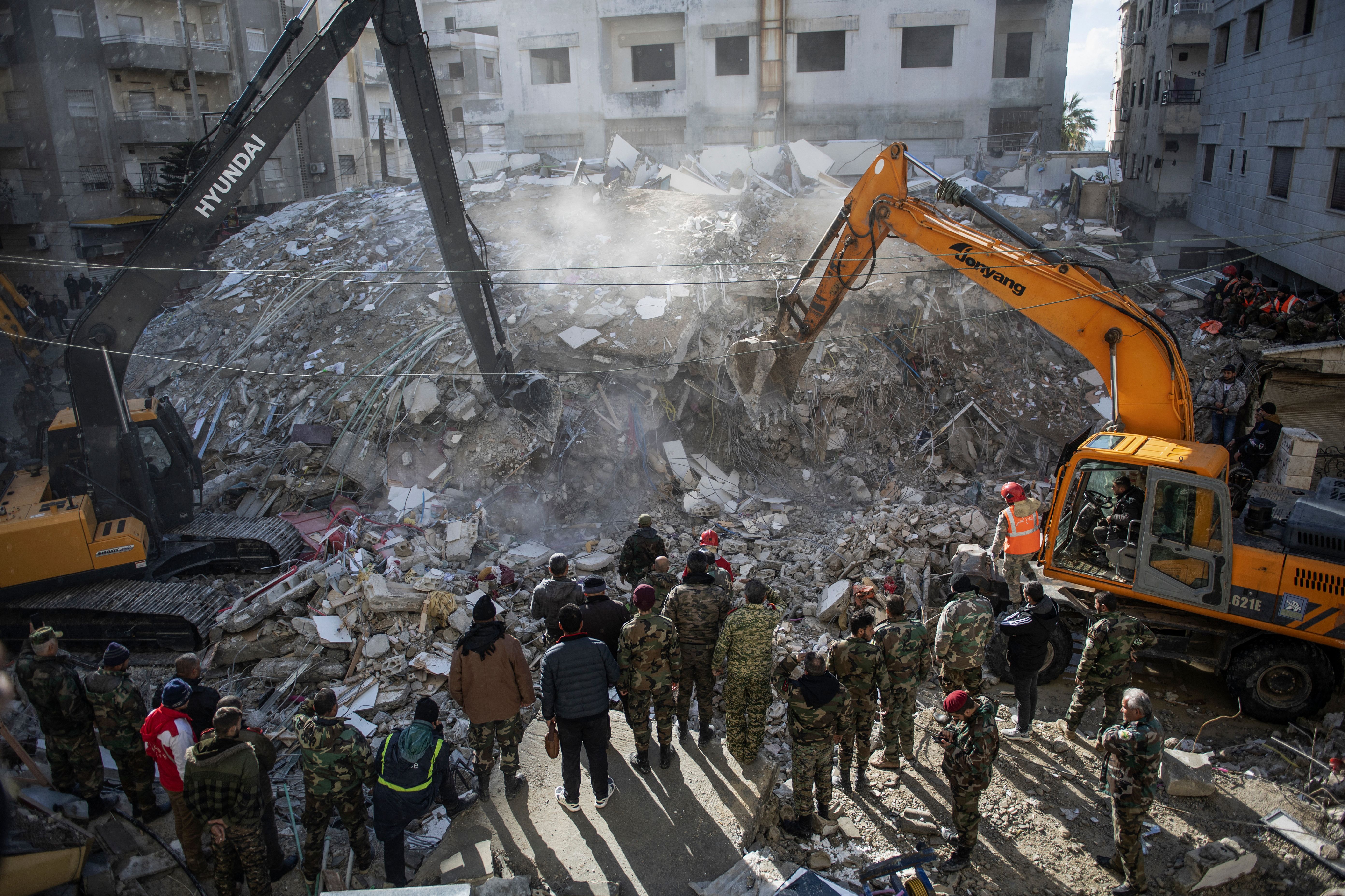 ]Rescue workers search for survivors in the rubble of a collapsed building in Jableh, a town in Syria’s Latakia province, Feb. 7, 2023. A massive rescue effort in Turkey and Syria is hampered by frigid weather in a race against time to find survivors under buildings flattened by powerful quakes that killed more than 5,000 people.