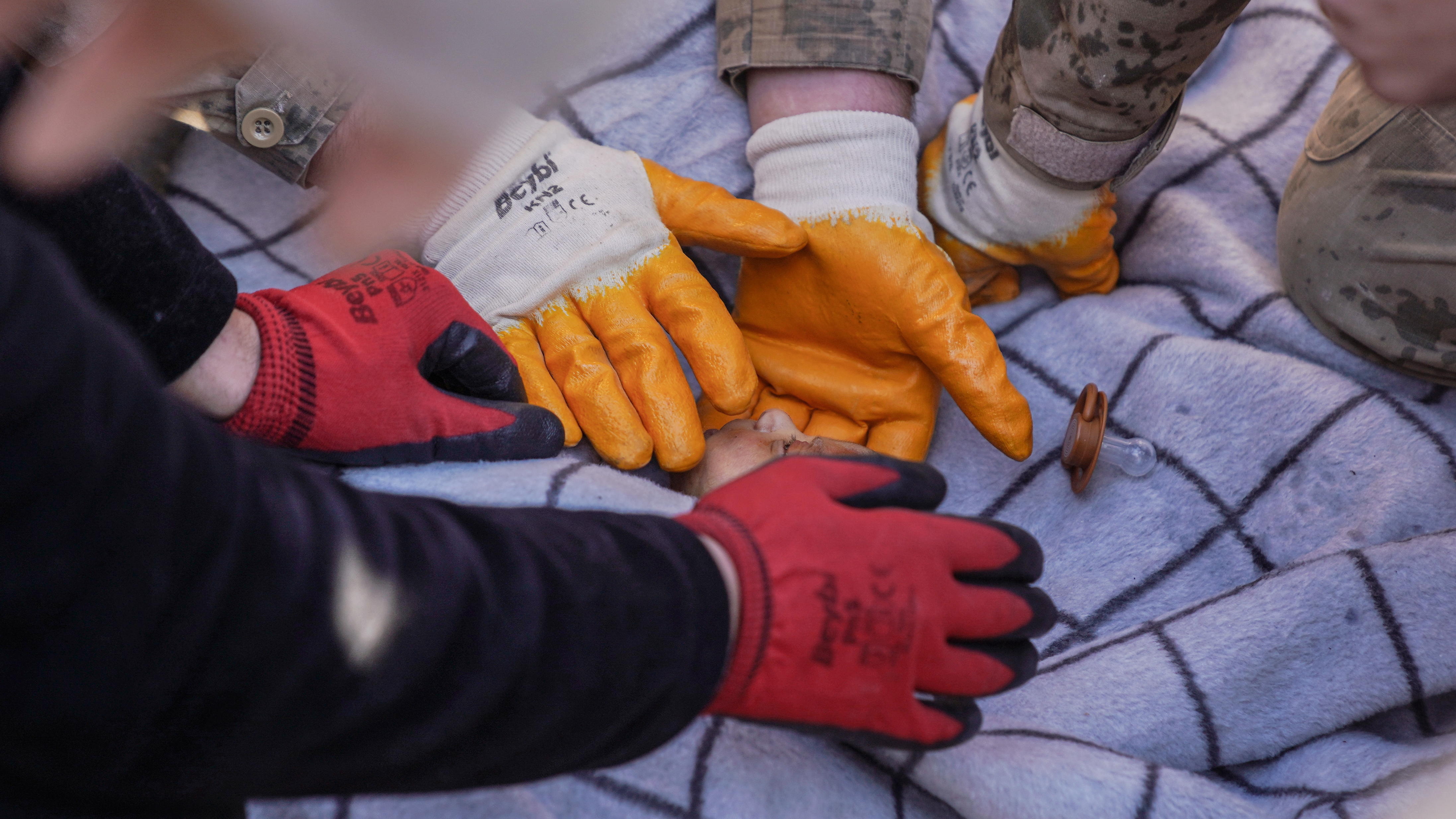 Soldiers examine a newborn baby rescued from the rubble in Hatay, Turkey, Feb. 8, 2023. The newborn, 20-days old, was rescued 59 hours after the earthquake and reported to be in good health. Rescue efforts continue for his mother.