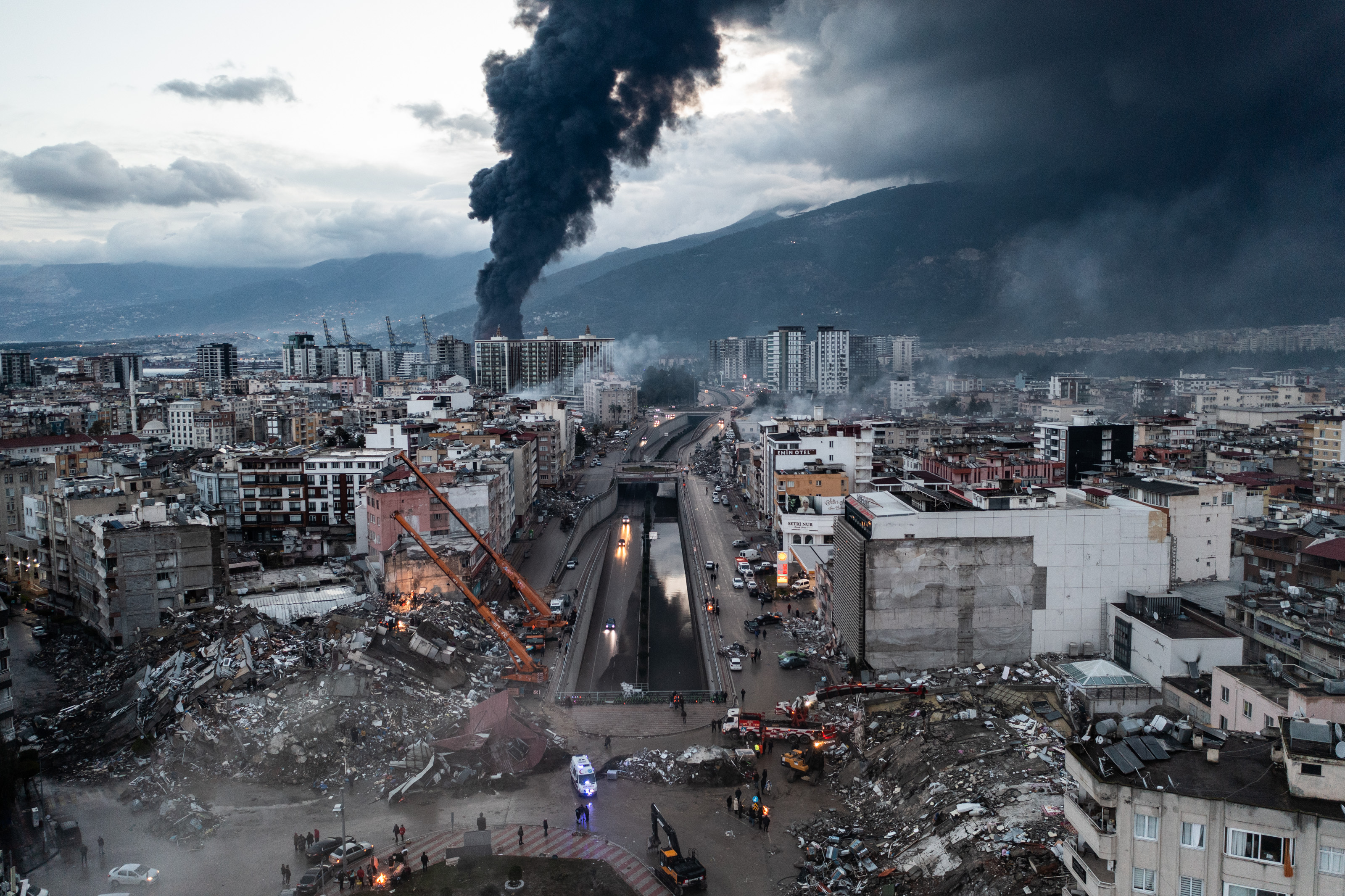 Smoke billows from the Iskenderun Port as rescue workers work at the scene of a collapsed building, Feb. 7, 2023, in Iskenderun, Turkey. A 7.8-magnitude earthquake hit near Gaziantep, Turkey, causing widespread destruction in southeastern Turkey and northern Syria.