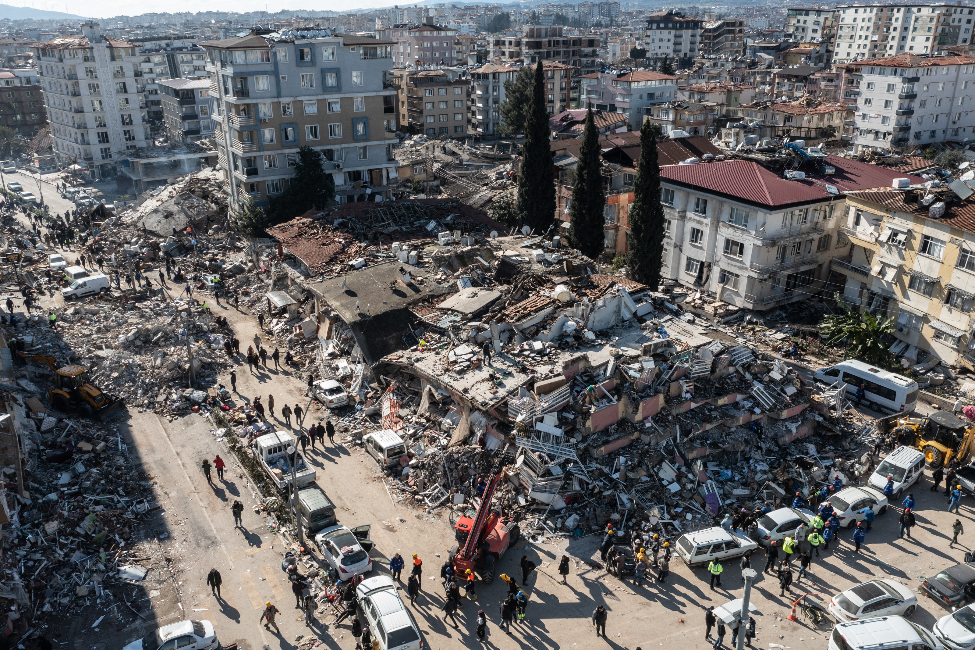 People gather around the rubble of collapsed buildings, Feb. 8, 2023, in Hatay, Turkey. A 7.8-magnitude earthquake hit near Gaziantep, Turkey, in the early hours of Monday, followed by another 7.5-magnitude tremor just after midday. The quakes caused widespread destruction in southern Turkey and northern Syria and were felt in nearby countries.