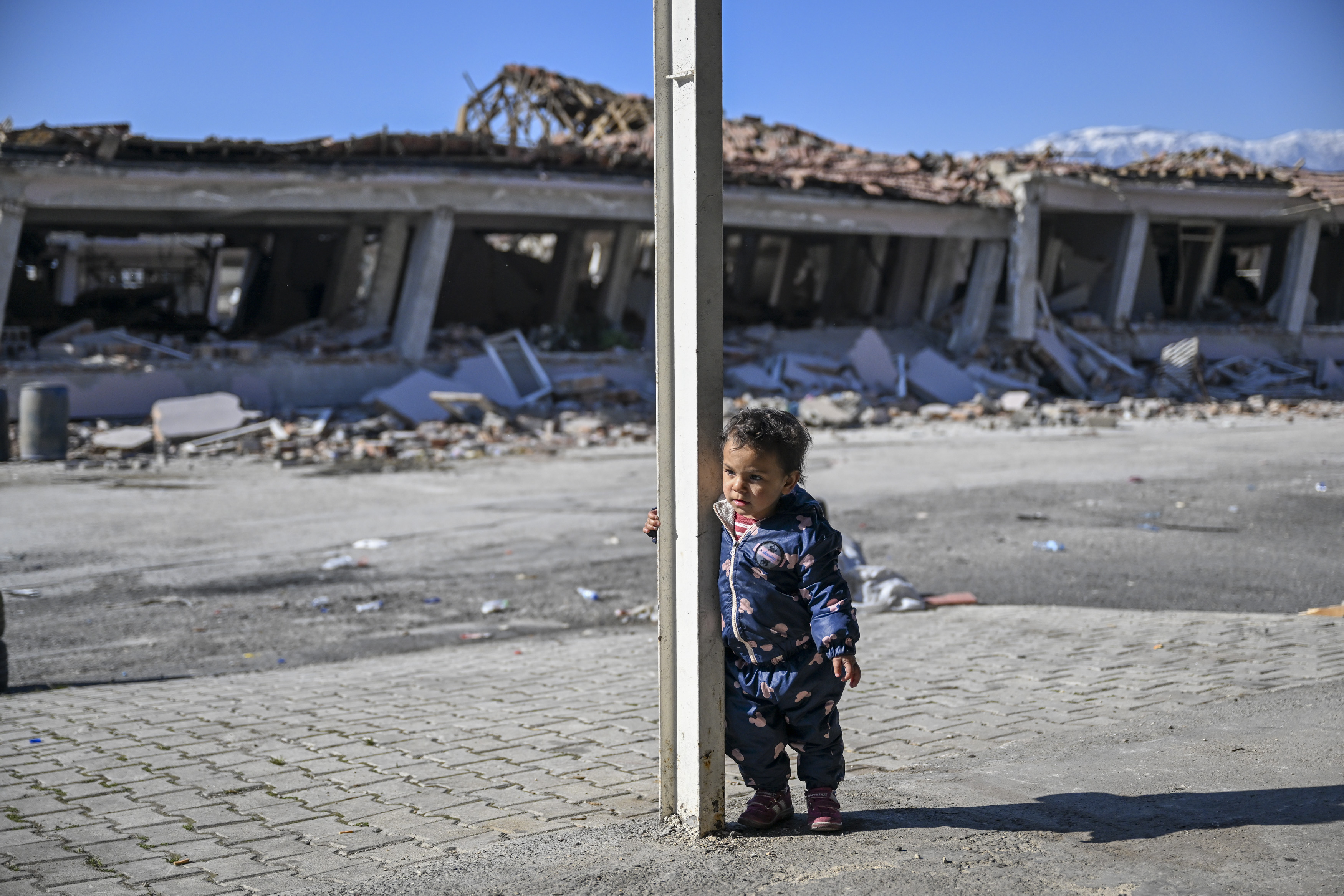 A young child stand in destroyed street of an Uzbek village damaged by earthquakes, Feb. 21, 2023 in Hatay, Turkey. The death toll from a catastrophic earthquake that hit Turkey and Syria has topped 46,000, with search and rescue teams starting to wind down their work.