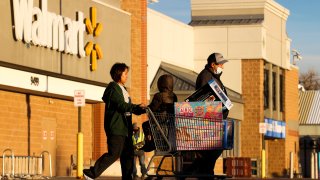 A family of shoppers walk out of Walmart with a full shopping cart on November 26, 2021 in Westminster, Colorado.