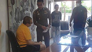 Peter Coker Jr., left, is issued search warrants from police at his villa on the southern resort island of Phuket, Thailand, Jan. 11, 2023.