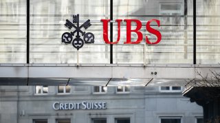 A sign and logo of Credit Suisse bank is seen beneath a sign of Swiss giant banking UBS in Zurich on March 20, 2023.