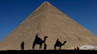 FILE – Policemen are silhouetted against the Great Pyramid in Giza, Egypt, Dec 12, 2012. Egypt unveiled on Thursday, March 2, 2023, the discovery of a 9-meter-long chamber inside the Great Pyramid of Giza, the first to be found on the structure’s north side.