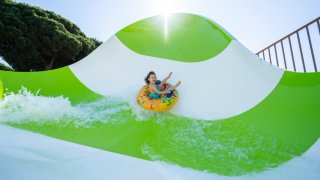 Kid on tube on green and white waterslide