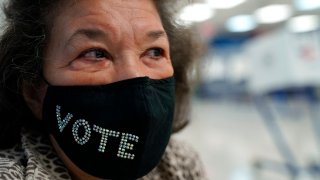 Election worker wears face mask with "vote" across the front.
