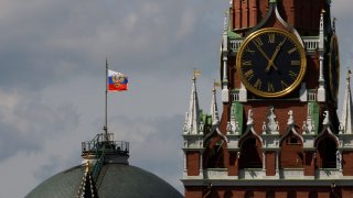 The Russian flag flies on the dome of the Kremlin Senate building behind Spasskaya Tower, while the roof shows what appears to be marks from the recent drone incident, in central Moscow, Russia, May 4, 2023. 