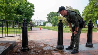 A U.S. Park Police officer inspects a security barrier for damage in Lafayette Square park near the White House, Tuesday, May 23, 2023, in Washington.