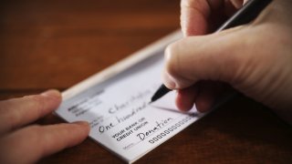 A person writes a check for a donation