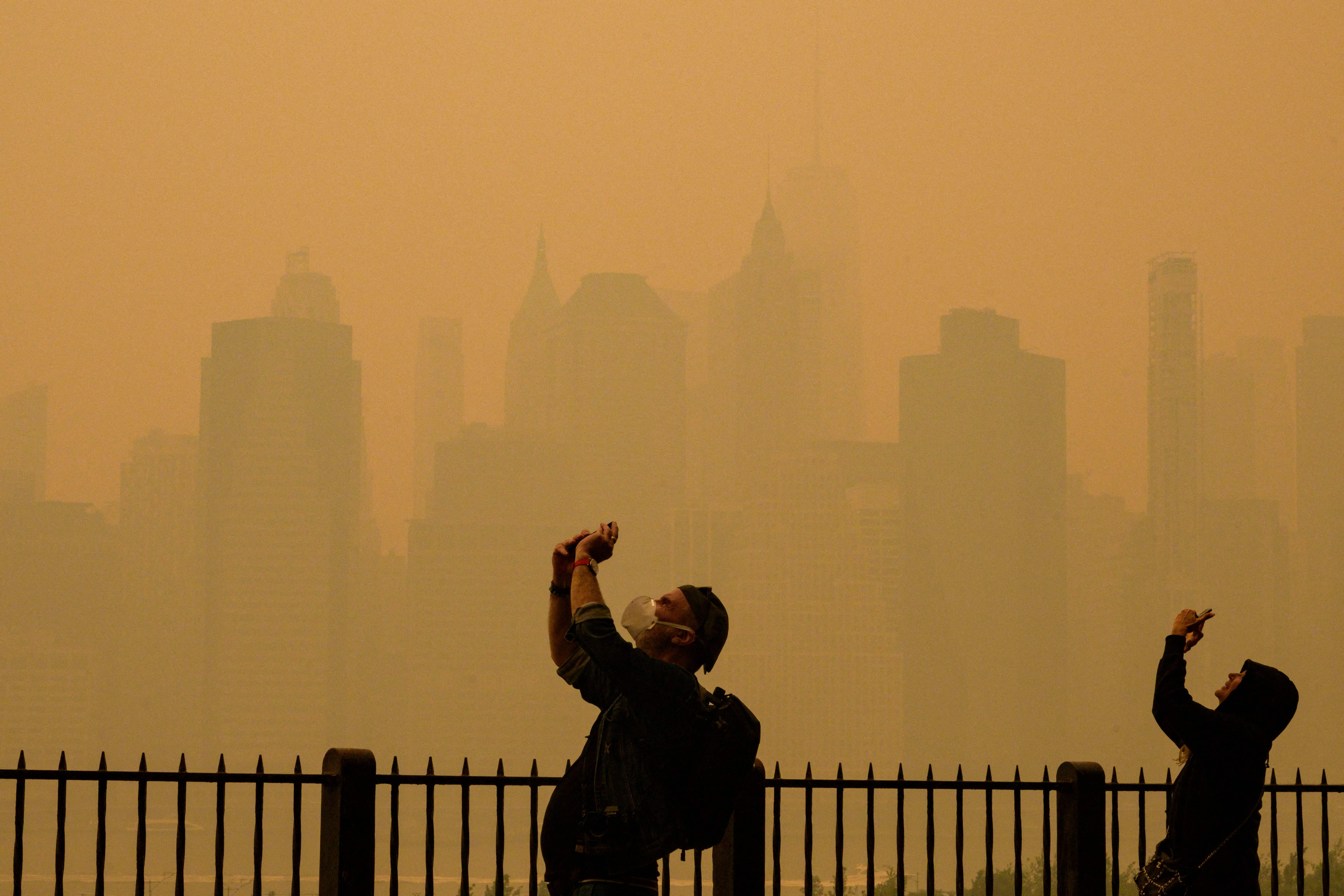 People take photos of the sun in Central Park as smoke from wildfires in Canada causes hazy conditions in New York City, June 7, 2023.