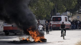 Tires burn surging clashes between Israeli forces and Palestinian militants in the West Bank city of Jenin Monday, June 19, 2023. Israeli helicopter gunships struck targets in the West Bank, during a fierce gunbattle in which Palestinian militants detonated a roadside bomb next to an Israeli military vehicle. At least three Palestinians, including a 15-year-old boy, were killed. Twenty-nine Palestinians and seven Israeli border police and soldiers were wounded. The Israeli military said troops came under fire during an arrest and shot back at gunmen. (AP Photo/Majdi Mohammed)