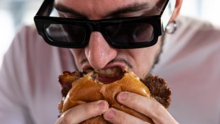 A man bites into a cheeseburger. (Photo by Emanuele Cremaschi/Getty Images)