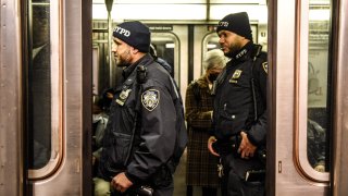New York City Police Department officers patrol a subway car in New York