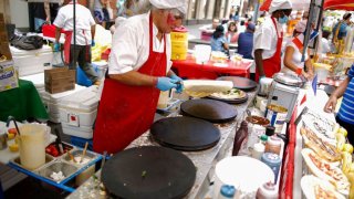 a man makes crepes at the bastille day festival in nyc