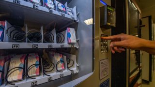 A person demonstrates how to purchase a carton out of the “morning-after” pill, Plan-B, vending machine that sits in the basement of the student union building on the Boston University Campus in Boston, Massachusetts on July 26, 2022.