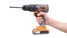 A hand holding a drill against a white background.