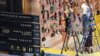 Employees prepare a window display at a Kate Spade store in The Shoppes at Marina Bay Sands shopping mall in Singapore, June 19, 2020.