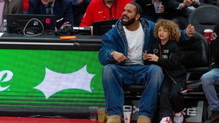 Canadian rapper Drake and his son Adonis watch at the court during the Toronto Raptors v Charlotte Hornets NBA regular season