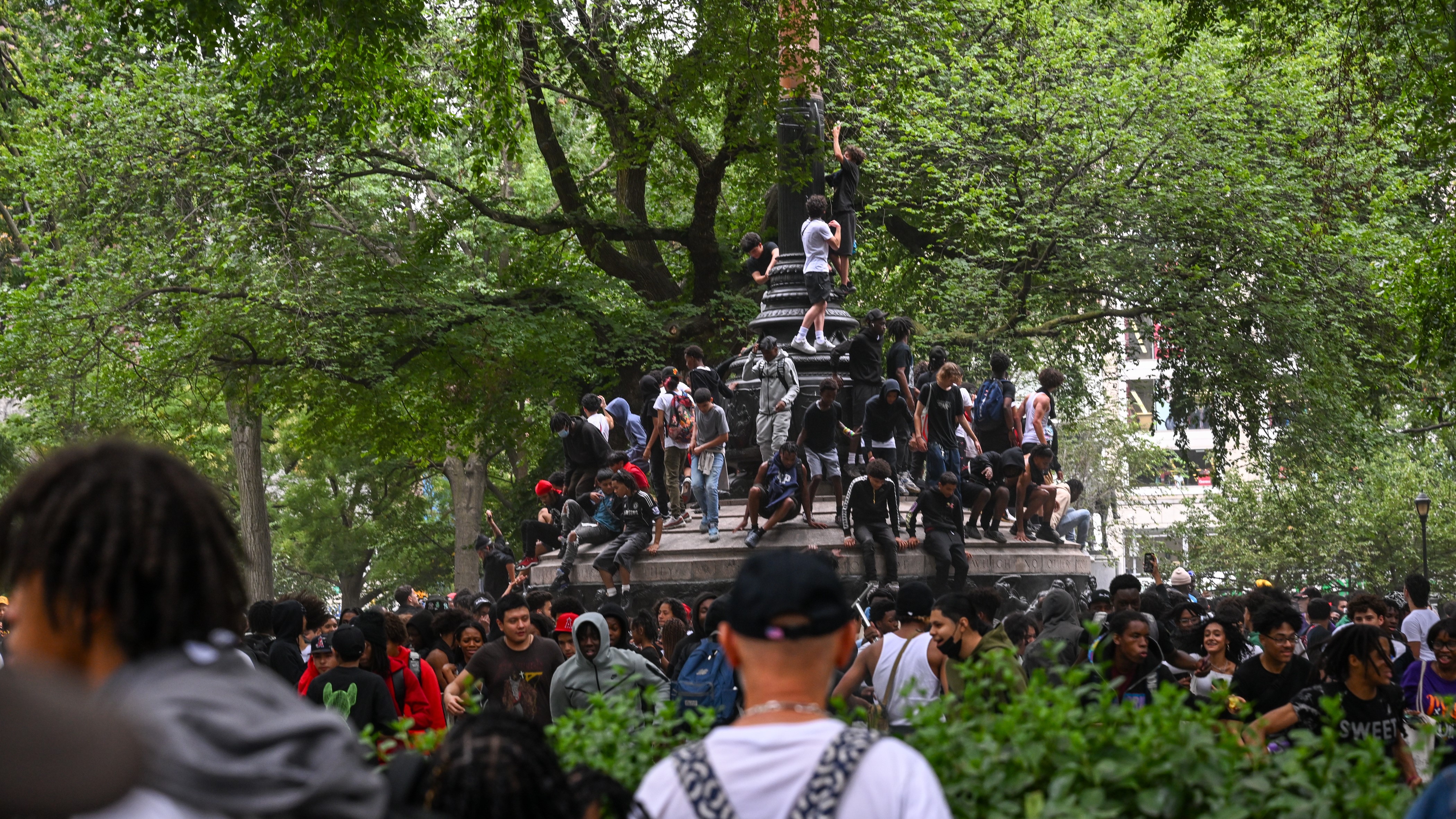 People climb on top of a sculpture in Union Square Park as Members of the NYPD respond to the disruptions caused by large crowds during a “giveaway” event. (Photo by Alexi J. Rosenfeld/Getty Images)