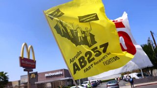 Flags are flown at a car caravan and rally of fast food workers and supporters for passage of AB 257, a fast-food worker health and safety bill, on April 16, 2021 in the Boyle Heights neighborhood of Los Angeles, California.