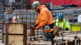 A construction worker wires rebar for a foundation