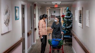 Tina Sandri, CEO of Forest Hills of DC senior living facility, left, helps resident Courtney Andrews back to her room