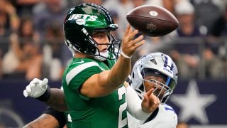 New York Jets quarterback Zach Wilson passes under pressure from Dallas Cowboys linebacker Micah Parsons