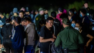 FILE PHOTO of Chinese migrants speaking to a border patrol officer before being processed after they crossed the Rio Grande into the U.S. on May 05, 2022 in Roma, Texas. (Photo by Brandon Bell/Getty Images)