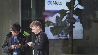 People using their mobile phones outside the offices of Meta, the parent company of Facebook and Instagram, in King’s Cross, London.