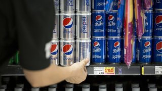 A worker organizes cans of PepsiCo Inc. soda on a shelf inside a grocery store in Phoenix, Arizona, U.S., on Thursday, July 6, 2017. PepsiCo Inc. is scheduled to release earnings figures on July 11. Photographer: Caitlin O’Hara/Bloomberg via Getty Images