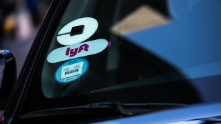 Uber Technologies Inc. and Lyft Inc. stickers are displayed on a vehicle.