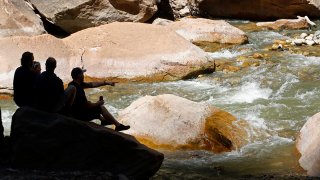 FILE - Hikers take a break along the North Fork of the Virgin River in Zion National Park on May 15, 2020, in Springdale, Utah.