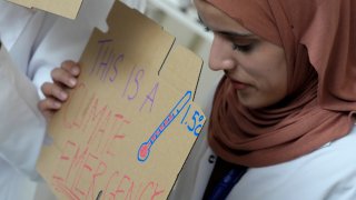 Sarah Neggazi holds a sign that reads "this is a climate emergency" during a demonstration at the COP28 U.N. Climate Summit, Sunday, Dec. 3, 2023, in Dubai, United Arab Emirates.