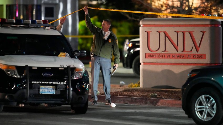 A police officer walks under crime scene tape