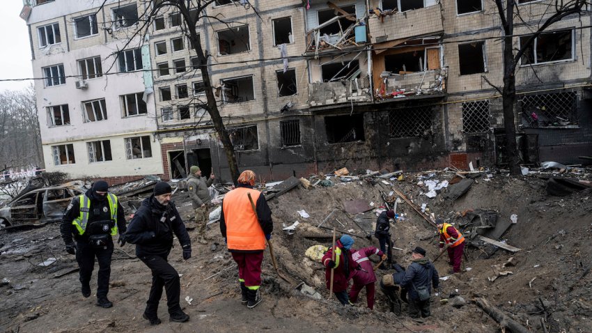 Investigators look for fragments of a rocket inside a crater after a Russian rocket attack at a residential neighbourhood in Kyiv, Ukraine, Wednesday, Dec. 13, 2023.